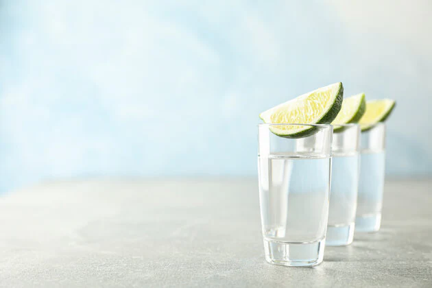 Três shots de tequila com fatias de limão – uma cena clássica ao falar dessa bebida mexicana.